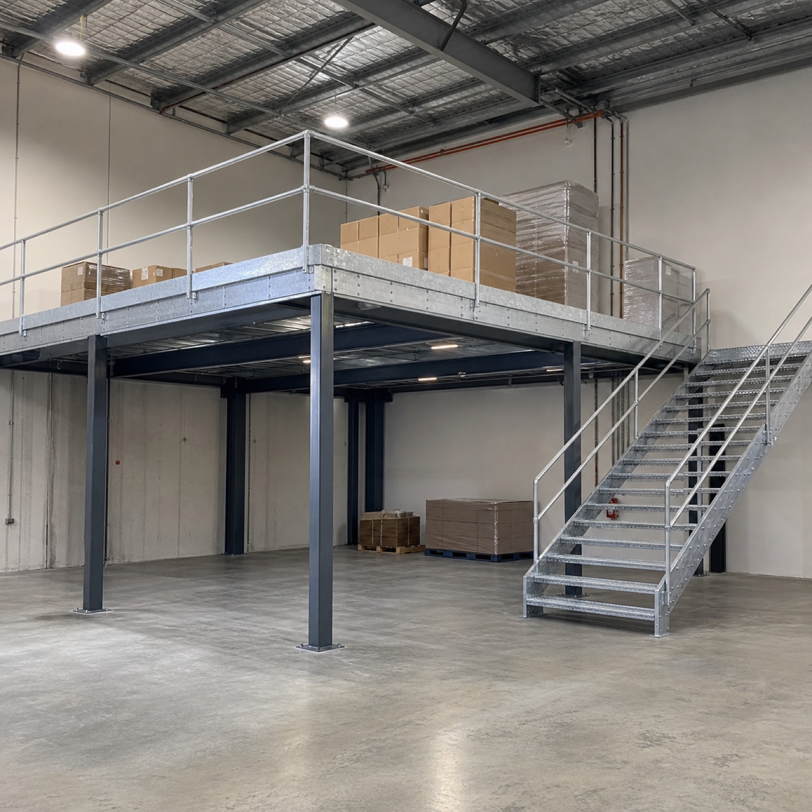 Galvanised mezzanine storage platform with stairs in a warehouse